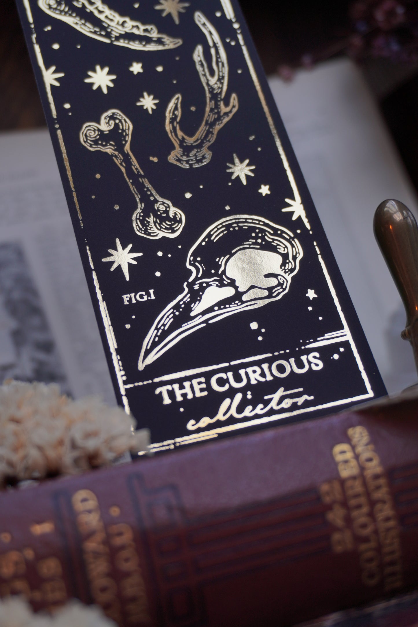 Black and gold bookmark on a candlelit background with vintage books and decorative elements