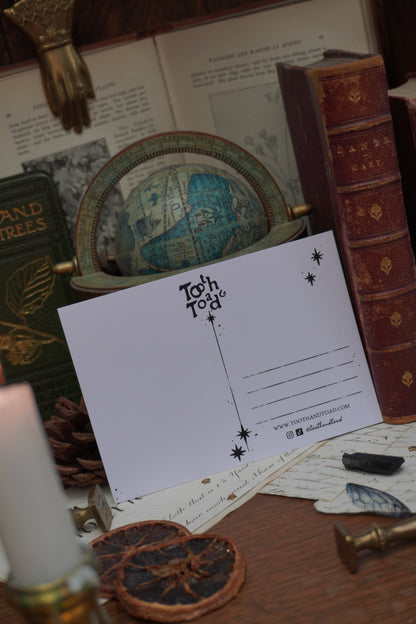 A white postcard with black text, Tooth and Toad logo and stars against a background of vintage decorative elements, old books and a globe
